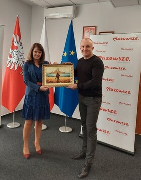 Orzełowska i przewodniczący miasta Miżhirja pozują do zdjęcia. oboje trzymają obraz z widokiem.