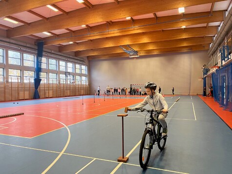 Chłopiec jedzie rowerem przez tor rowerowy zrobiony w sali gimnastycznej