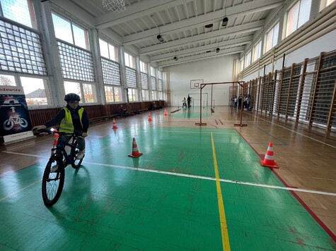 Chłopiec jedzie rowerem po sali gimnastycznej