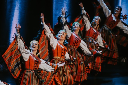 Tancerze w ludowych strojach tańczą na scenie