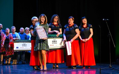 Janina Ewa Orzełowska stoi na scenie wraz z nagrodzonymi liderkami. Prezentuje dyplom