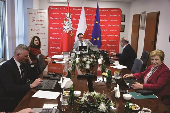 Zarząd Województwa Mazowieckiego zasiada przy stole podczas zdalnej sesji.