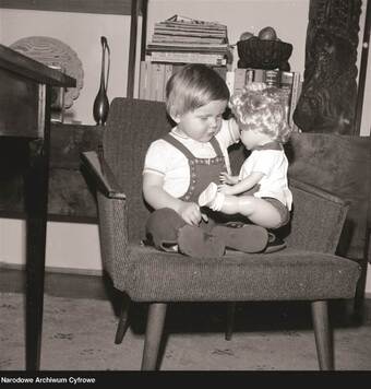 mała dziewczynka siedzi z lalką na fotelu