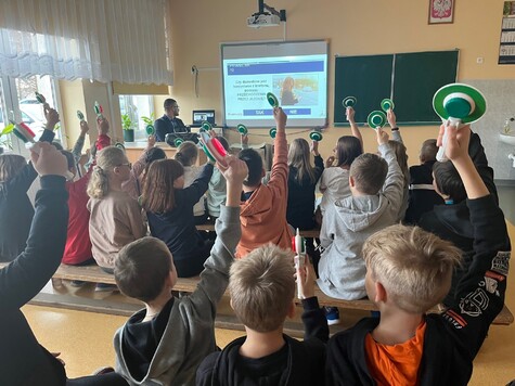 Dzieci podnoszą ręce podczas wykładu interaktywnego