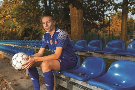 młody piłkarz siedzi na trybunach przy boisku