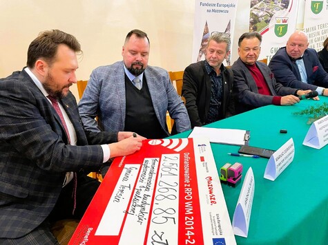 Wiceprzewodniczący sejmiku Marcin Podsędek podpisuje pamiątkowy czek