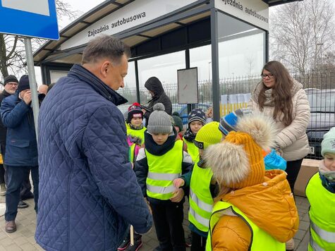 Marszałek z dziećmi przed przystankiem autobusowym