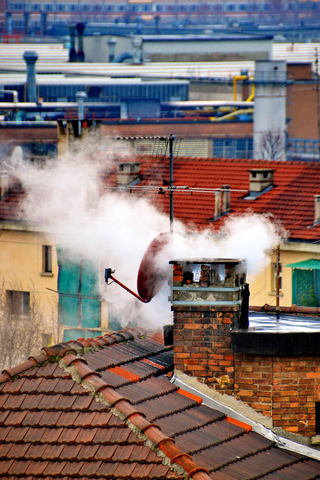 Dymiący komin na dachu domu