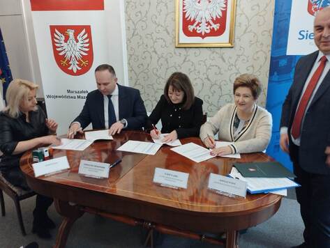 Wójt gminy Korczew ( po lewej), Janina Ewa Orzełowska (w środku) i Elżbieta Lanc (po prawej) podpisują przy stole umowę na dofinansowanie dla gminy Korczew 