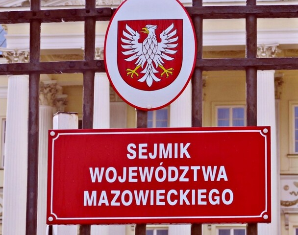 Tablica czerwona z napisem Sejmik Województwa Mazowieckiego, wyżej herb Mazowsza