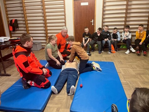 Dwóch ratowników instruuje dwóch uczniów, jak przeprowadzać resuscytację