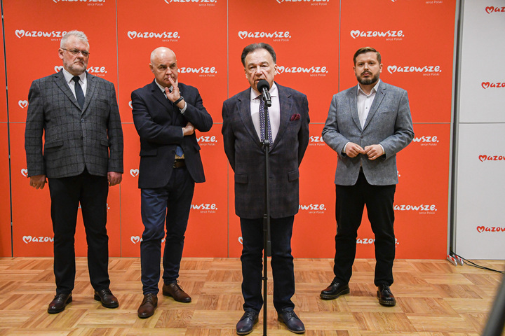 Czterech mężczyzn stoi na tle czerwonej ścianki