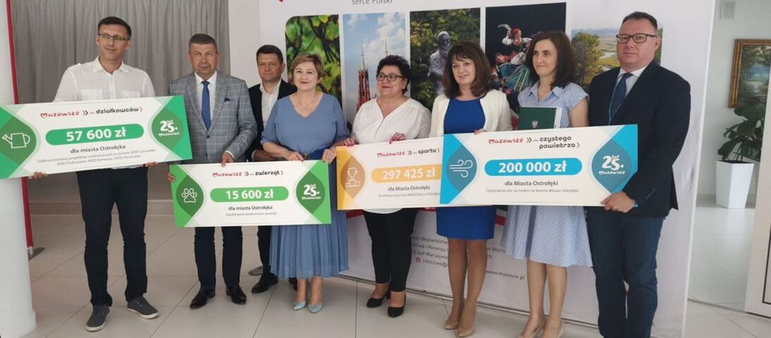 Elżbieta Lanc i Janina Ewa Orzełowska w towarzystwie beneficjentów z powiatu ostrołęckiego prezentują duże czeki