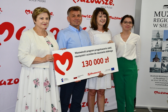Członkinie zarządu Janina Ewa Orzełowska i Elżbieta Lanc z beneficjentami, którzy trzymają czek
