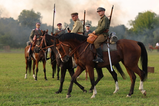 Żołnierze w ubraniach z epoki na koniach.