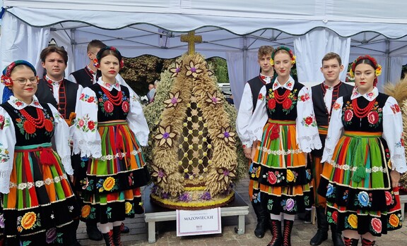 Członkowie zespołu w tradycyjnych strojach z wieńcem dożynkowym z Mazowsza