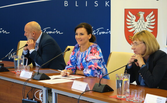 Przy stole siedzą burmistrz Wołomina Elżbieta Radwan, przewodnicząca komisji Anna Katarzyna Brzezińska, radny województwa mazowieckiego Piotr Kandyba
