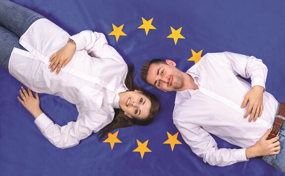 Dziewczyna i chłopak na tle flagi Unii Europejskiej